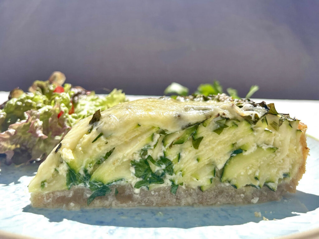 Vegetarisches Quiche-Rezept: Ein Stück Zucchini-Quiche auf einem Teller mit Salat