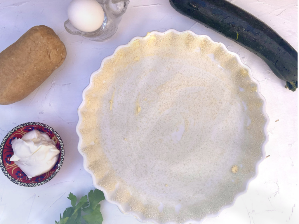 Zutaten für ein vegetarisches Quiche-Rezept mit Zucchini und Petersilie, einschließlich Dinkelvollkornteig, Zucchini, Ei und Crème Fraîche