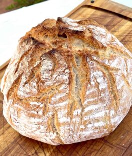Ein frisch gebackener Brotlaib auf einem Holzbrett.
