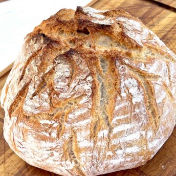 Ein frisch gebackener Brotlaib auf einem Holzbrett.