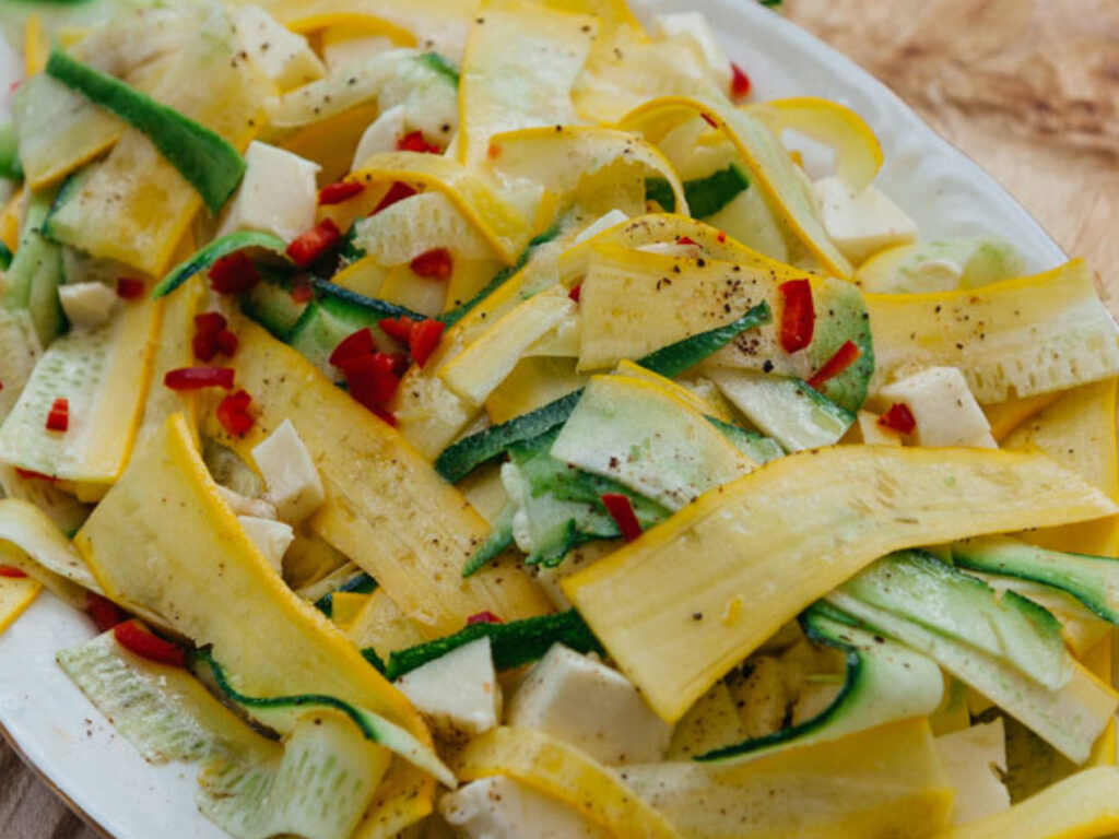 Gelbe und grüne Zucchinistreifen, Mozzarella und Chili