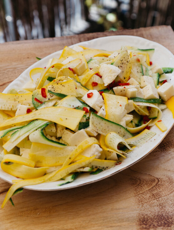 Frischer Zucchinisalat mit gelben und grünen Zucchinistreifen, Mozzarella und Chili