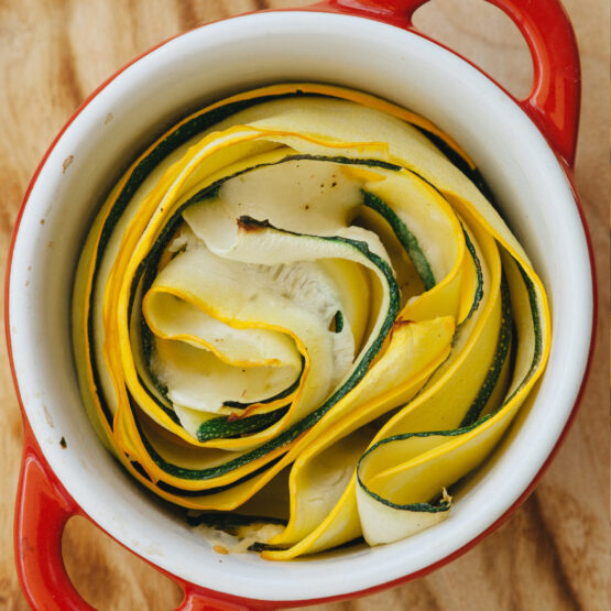 Vegetarisches Gericht mit Corquetten, kunstvoll geschichtet in einer roten Auflaufform