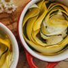 Grüne und gelbe Sommerkürbisse in Rosettenform in einer kleinen roten Backform, perfekt als vegetarische Beilage