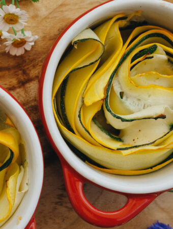 Grüne und gelbe Sommerkürbisse in Rosettenform in einer kleinen roten Backform, perfekt als vegetarische Beilage