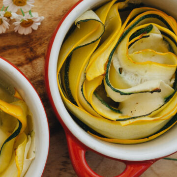 Grüne und gelbe Sommerkürbisse in Rosettenform in einer kleinen roten Backform, perfekt als vegetarische Beilage
