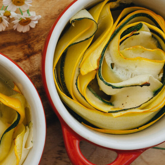Grüne und gelbe Sommerkürbisse in Rosettenform in einer kleinen roten Backform, perfekt als vegetarische Beilage
