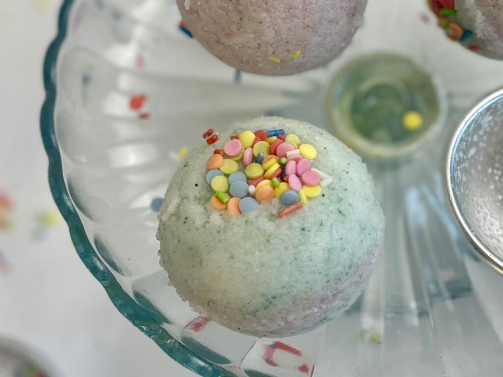 Glasplatte mit drei selbstgemachten Badebomben und Sprinkles