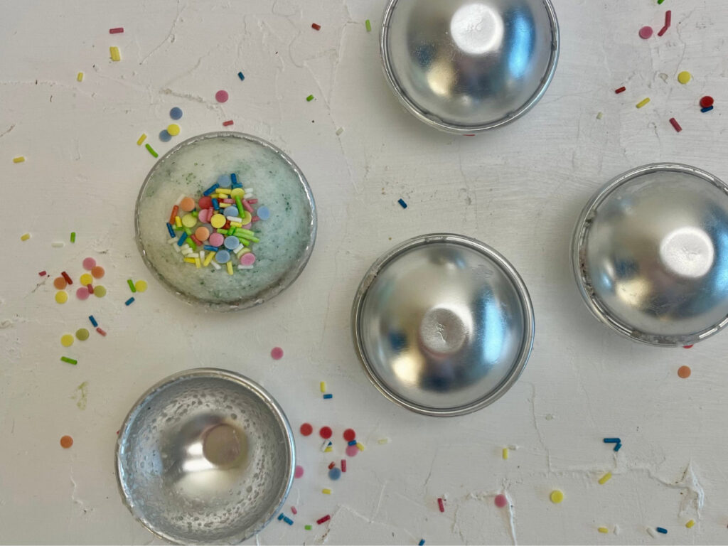 Runde Badebombenformen, eine davon gefüllt mit DIY Badebomben aus dem Rezept