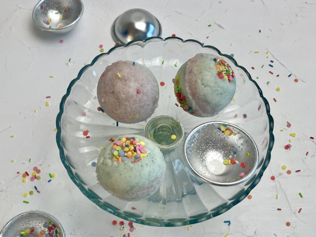 Glasplatte mit drei selbstgemachten Badebomben und Sprinkles, Badebomben RezeptBadebomben aus dem Rezept