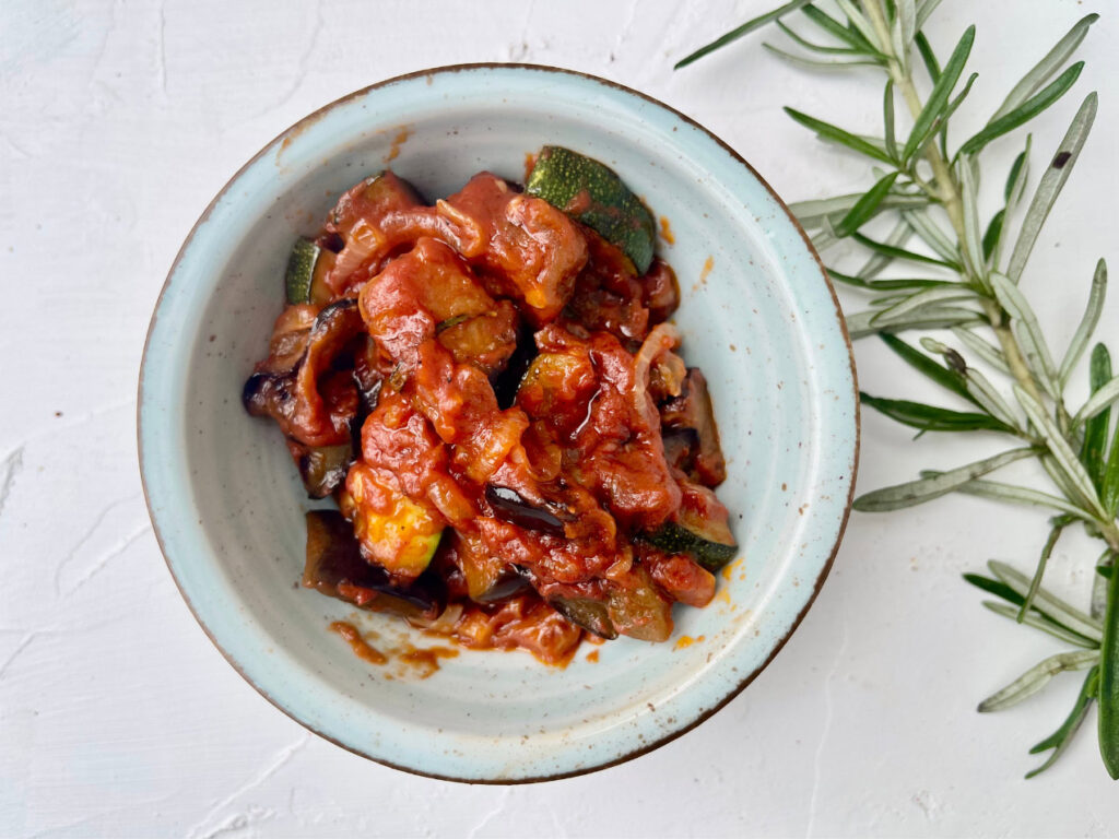 Schale mit Caponata, tomatig-glänzend, mit sichtbar gerösteten Auberginenwürfeln