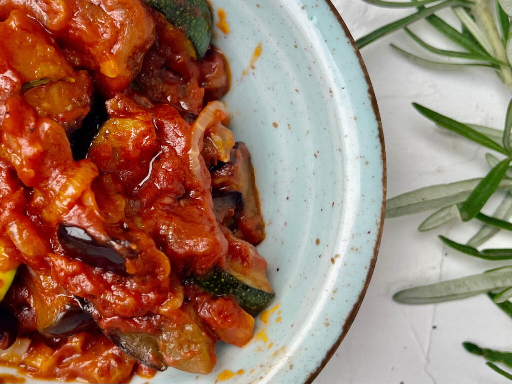 Caponata Rezept mit sizilianischer Tomatensauce und Auberginen, rustikal angerichtet in einer Schale