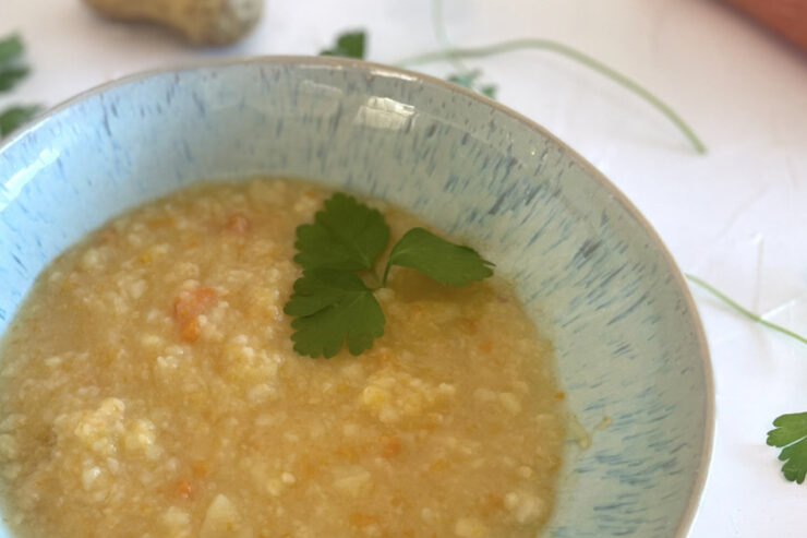 Rustikale Kartoffelsuppe wie bei Oma in einer hellblauen Schale, umgeben von frischer Petersilie und Kartoffeln.